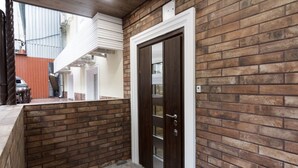 Parede exterior de tijolos com uma porta de madeira escura e detalhes em branco.