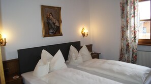 A hotel room with a large bed, two bedside tables, a wall-mounted painting, and two wall sconces.
