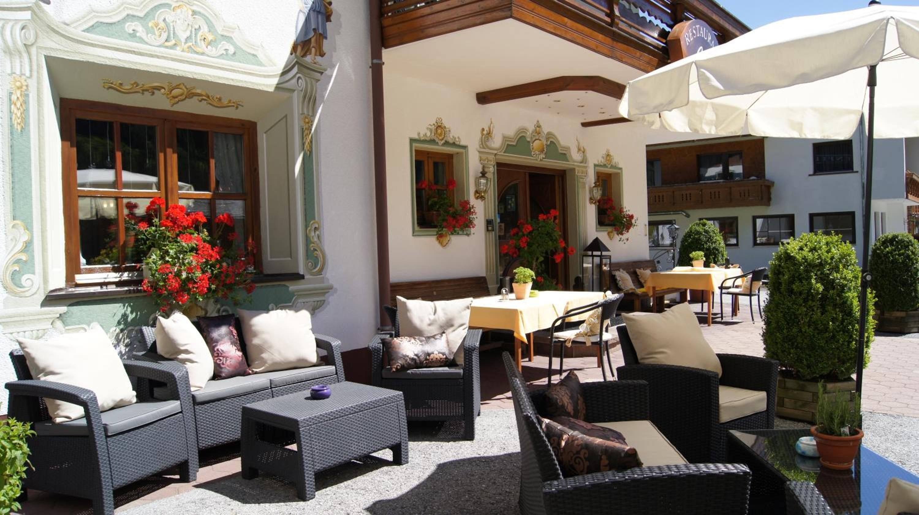 An outdoor seating area with wicker furniture, a table, and potted plants.