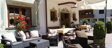 An outdoor seating area with wicker furniture, a table, and potted plants.