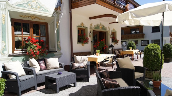 An outdoor seating area with wicker furniture, a table, and potted plants.