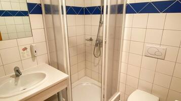 A bathroom with a glass-enclosed shower, a sink, and a toilet.