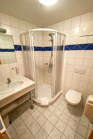 A bathroom with a glass-enclosed shower, a sink, and a toilet.