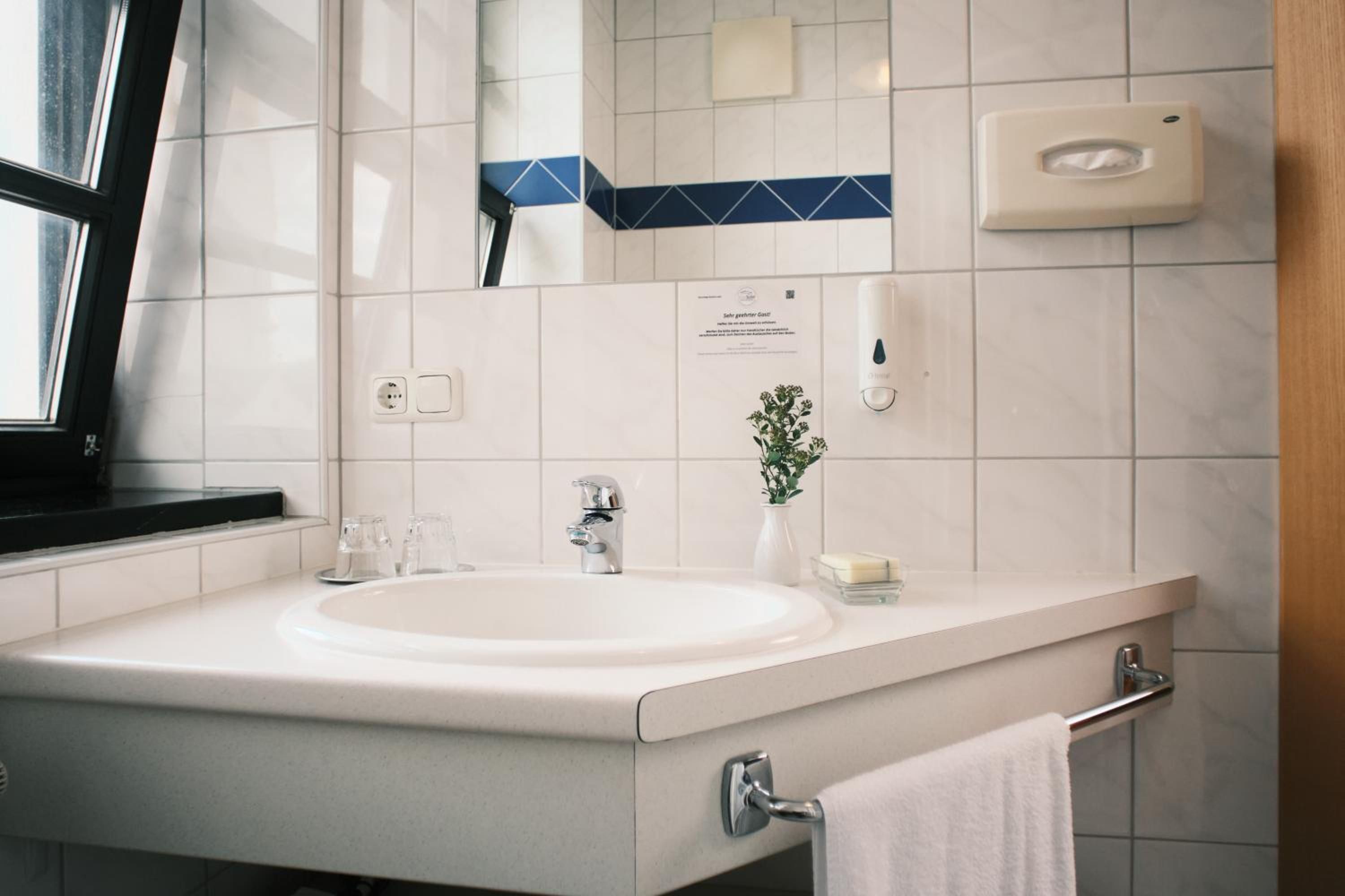 Ein modernes Badezimmer mit Waschbecken, Spiegel, Handtuchhalter und Seifenspender.