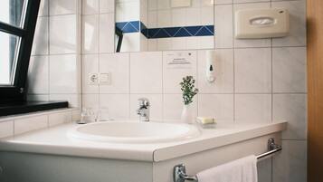 Ein modernes Badezimmer mit Waschbecken, Spiegel, Handtuchhalter und Seifenspender.