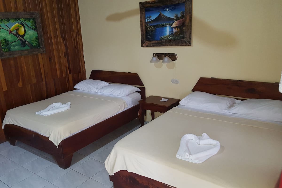 Ein Hotelzimmer mit zwei hölzernen Betten, weißen Laken und Bildern an den Wänden.