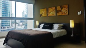 Habitación de hotel moderna con una cama grande, un ventilador de techo y vistas a la ciudad a través de la ventana.