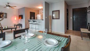Un comedor con una mesa preparada para cuatro personas, una zona de bar y una cocina al fondo.