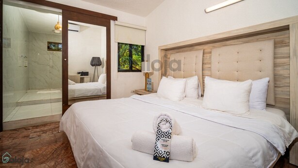 A hotel room with a large bed, a wooden headboard, a bedside table with a lamp, and a glass-enclosed shower area. - Casa Maraf Hotel Boutique - Adults Only (Cancun)