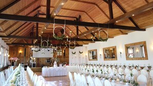 A banquet hall with a high wooden ceiling, long tables set for a formal event, and decorative wreaths hanging from the ceiling. - Hotel Grabinger (Schwandorf)