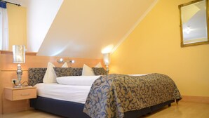 A bedroom with a bed, bedside lamps, a nightstand, and a mirror on the wall. - Hotel Grabinger (Schwandorf)
