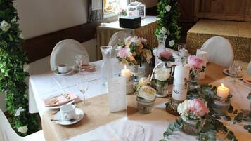 Una mesa dispuesta para un evento formal, con centros de mesa florales, velas y un menú.