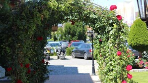 A paved pathway leading through a rose-covered archway. - Hotel Grabinger (Schwandorf)