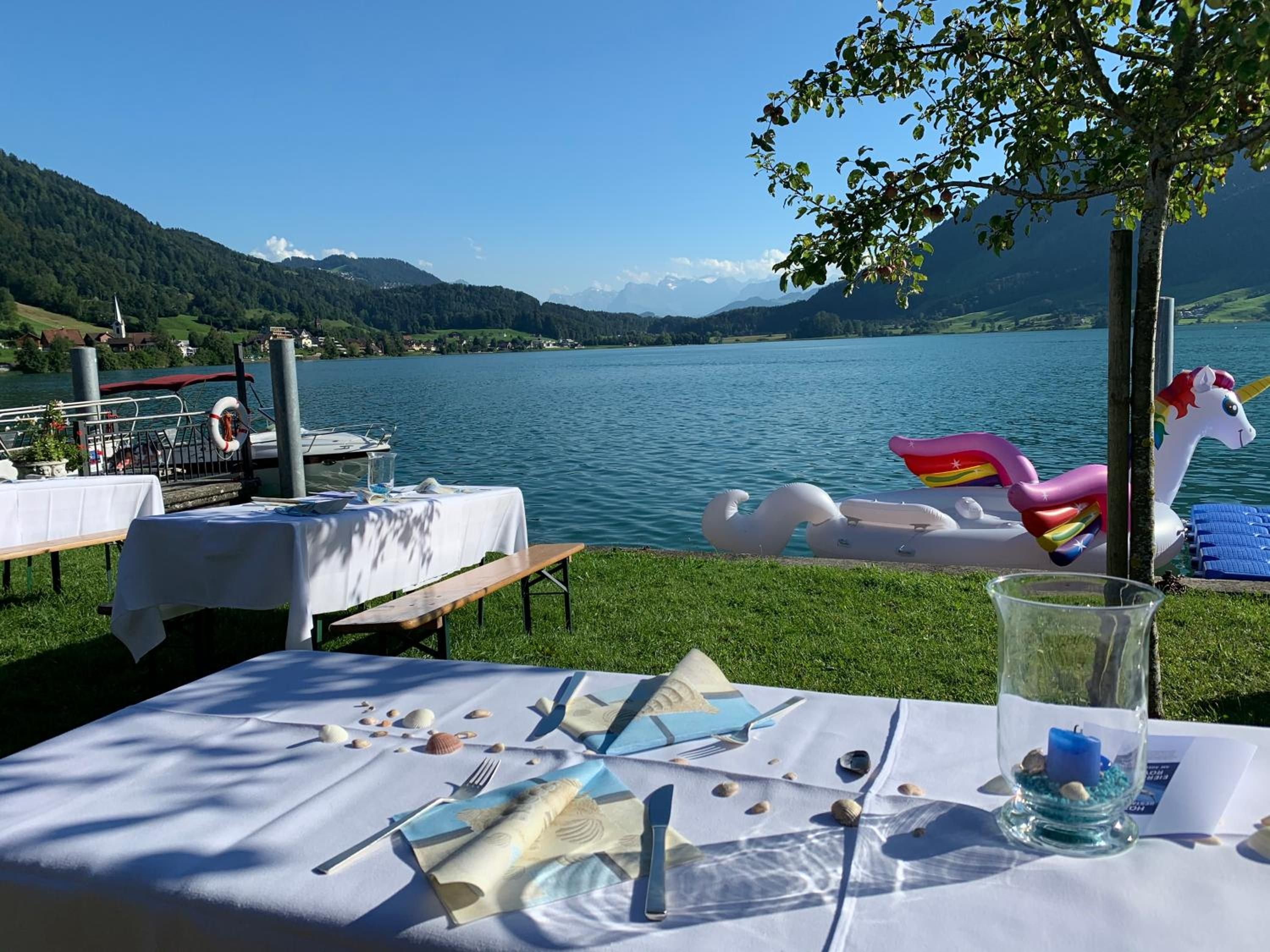 Montaje para comer junto al lago con mesas, un flotador de cisne y un flotador con forma de unicornio.