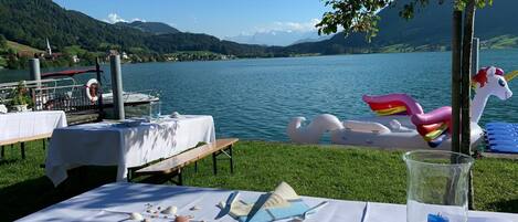 Montaje para comer junto al lago con mesas, un flotador de cisne y un flotador con forma de unicornio.