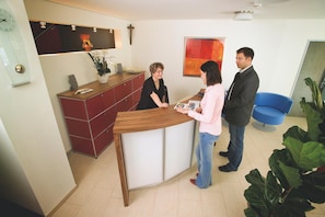 Una zona de recepción con un mostrador de madera, un armario rojo y una silla azul.