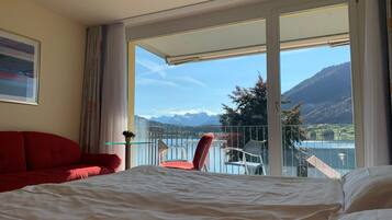 Ein Hotelzimmer mit einem Bett, einem roten Sofa, einem Sessel und einem Balkon mit Bergblick.