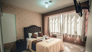 A neatly arranged bedroom with a bed, bedside table, and a desk with a chair. - Hostal Spring II (Huánuco)