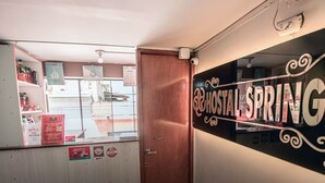 A room with a wooden door, a mirror reflecting a room with shelves and a sign that reads "HOSTAL ESPRING". - Hostal Spring II (Huánuco)