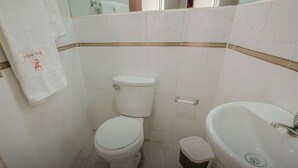 A small bathroom with a toilet, sink, and a towel hanging on the wall. - Hostal Spring II (Huánuco)