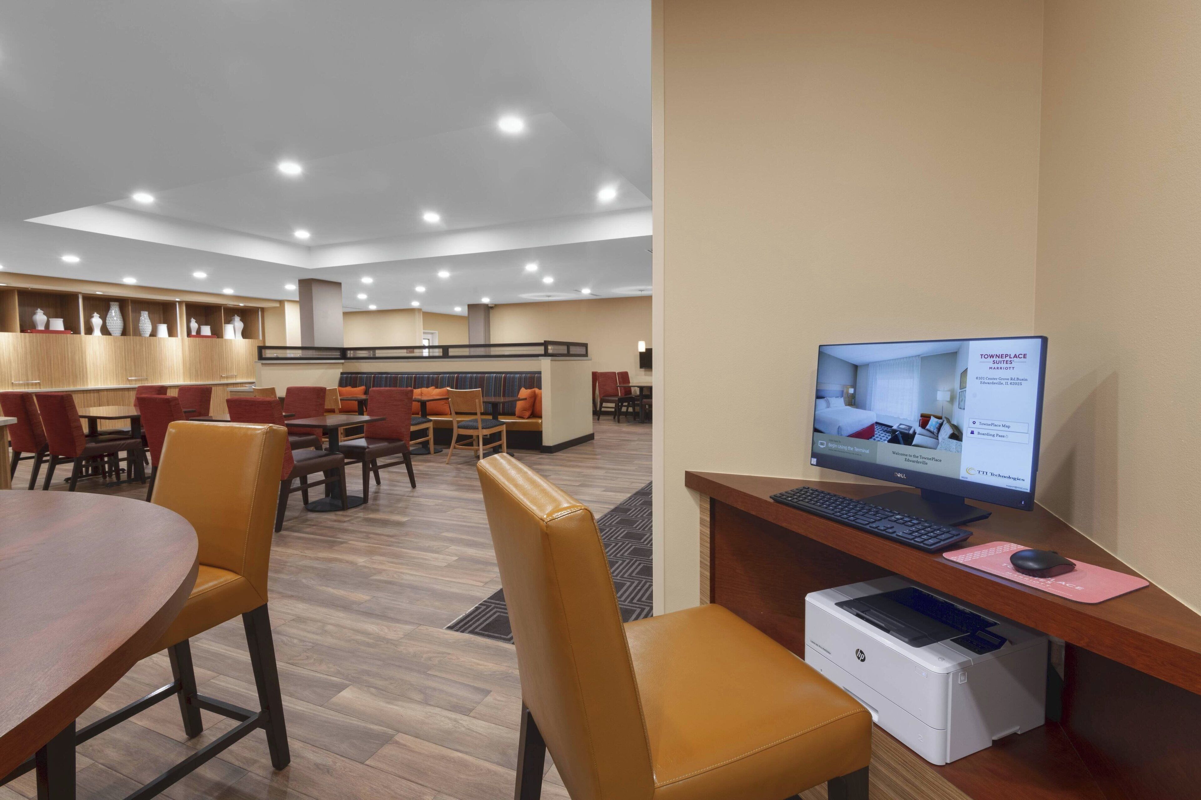 A hotel lobby with a reception desk, computer, printer, and seating area.
