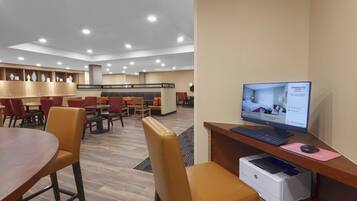 A hotel lobby with a reception desk, computer, printer, and seating area.