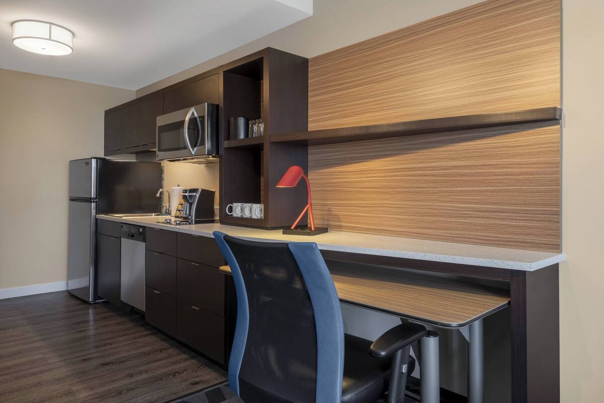 Una cocina compacta con microondas, refrigerador y cafetera.