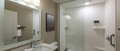 Een moderne badkamer met een grote spiegel, een wastafel, een toilet en een douche met glazen wanden.