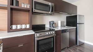 Una cocina moderna con electrodomésticos de acero inoxidable, armarios de madera y una encimera con una cafetera y tazas.