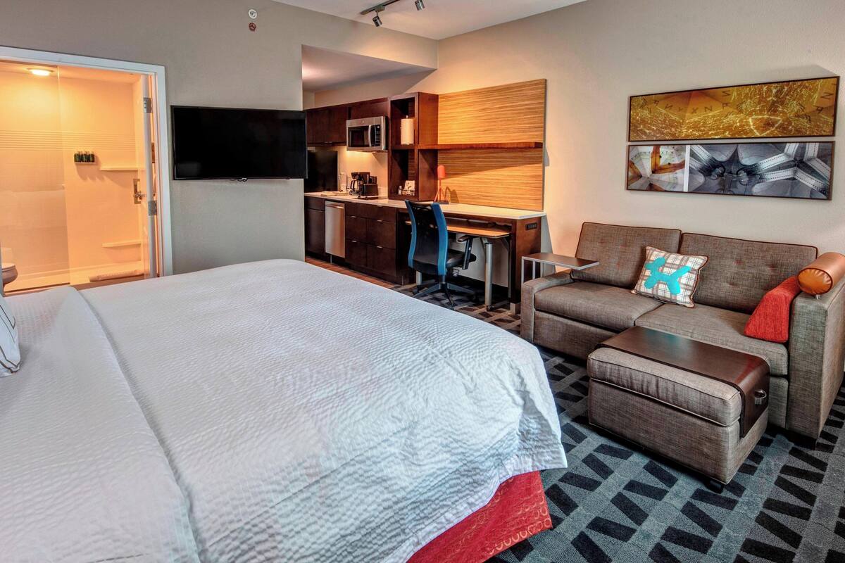 Une chambre d’hôtel avec un grand lit, un canapé, un bureau et une kitchenette.