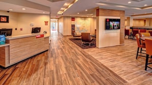A hotel lobby with a reception desk, seating area, and a map on the wall.