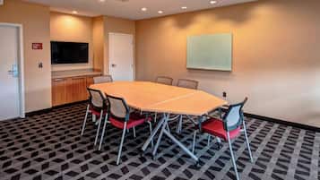 A conference room with a large table, chairs, a TV, and a whiteboard.