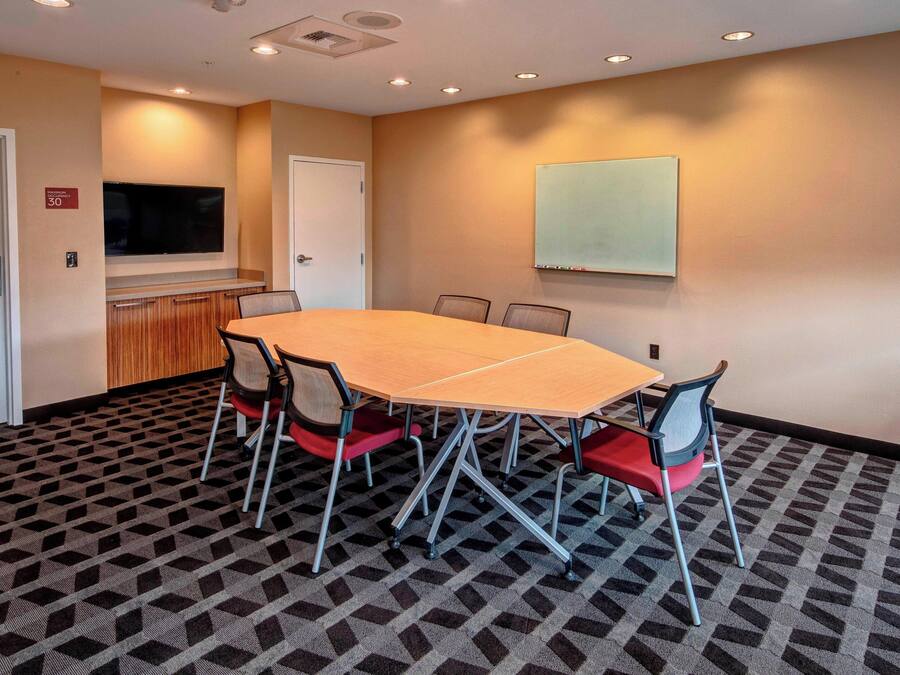 A conference room with a large table, chairs, a TV, and a whiteboard.