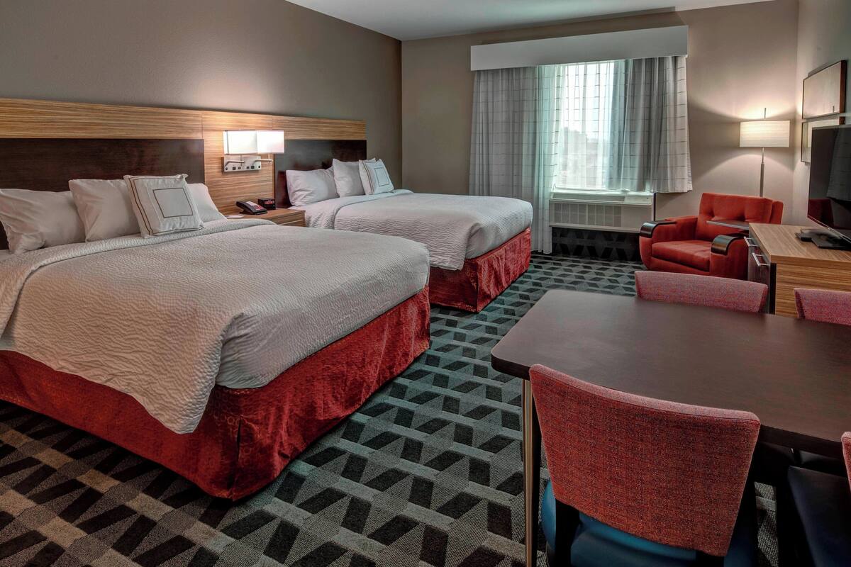 Une chambre d’hôtel avec deux lits, un bureau et une chaise.