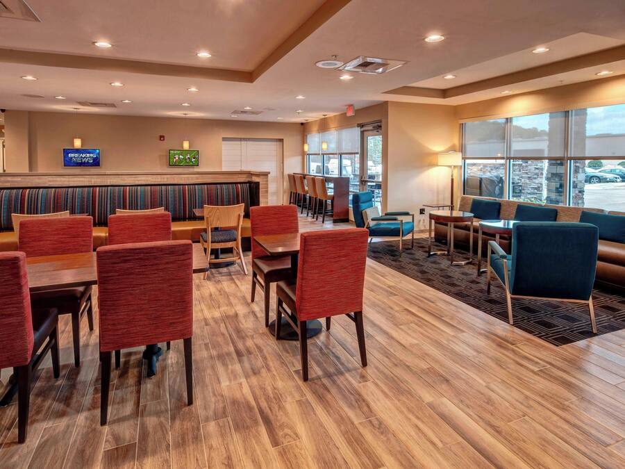 A hotel lobby with a seating area, a TV displaying news, and a fireplace.