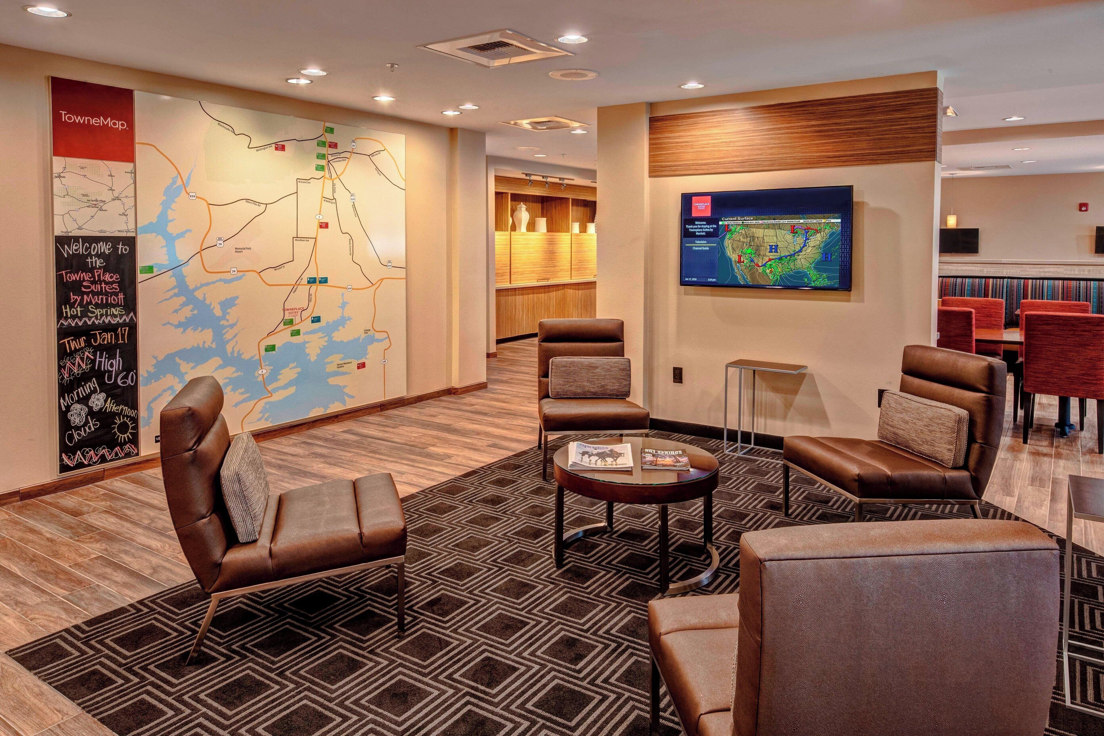 A lobby with leather chairs, a coffee table, a map on the wall, and a TV displaying a map.