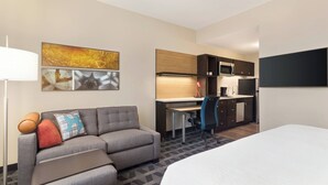Une chambre d’hôtel comprenant un lit, un canapé, un bureau et une kitchenette.