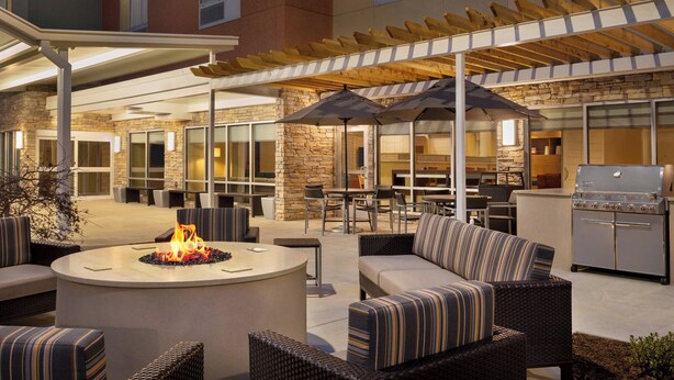 Une terrasse extérieure avec des sièges, un foyer et un espace barbecue.