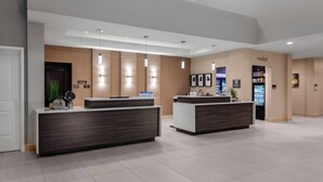 A modern hotel lobby with two reception desks, a vending machine, and a framed artwork on the wall. - Residence Inn by Marriott Phoenix Mesa East (Mesa)