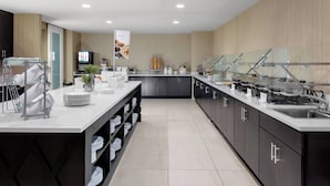 A modern kitchen with a central island, black cabinets, and a buffet setup. - Residence Inn by Marriott Phoenix Mesa East (Mesa)