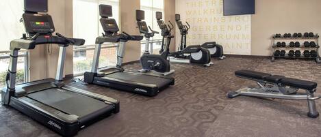 A gym with treadmills, ellipticals, and a bench press.