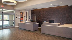 Un espace d’accueil au design moderne, avec un mur décoré d’un motif en briques, une porte d’entrée en verre et un comptoir doté d’un écran numérique.