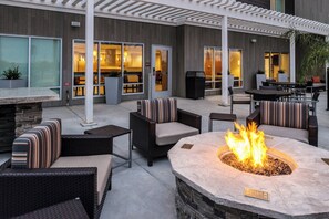 An outdoor patio area with wicker furniture, a stone fire pit, and a covered seating area. - TownePlace Suites by Marriott Merced (Merced)