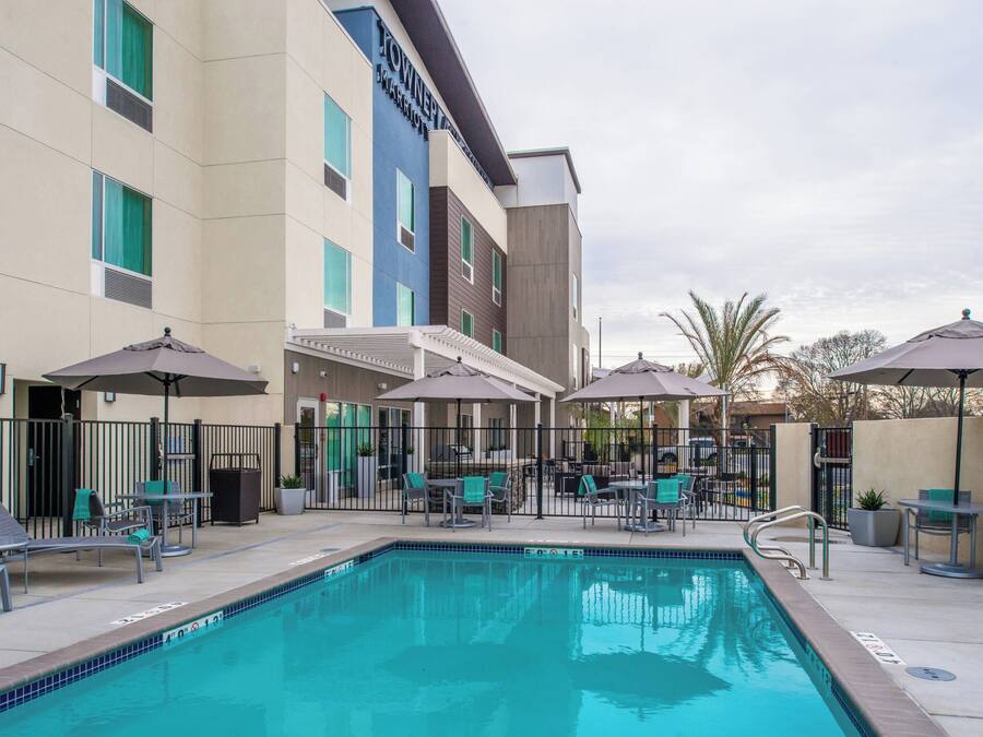 A hotel pool area with lounge chairs and umbrellas, surrounded by a fence.