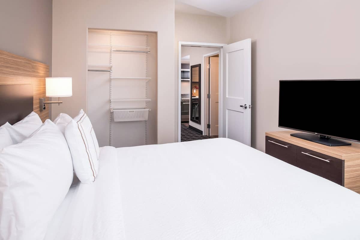 A hotel room with a bed, a TV, a wardrobe, and a walk-in closet.