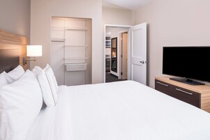 Una habitación de hotel con cama, televisión, armario y vestidor.