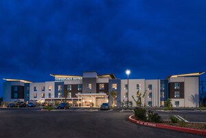 Un hotel TownePlace Suites Marriott con un diseño moderno, varios espacios de estacionamiento y una entrada bien iluminada.