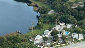 An aerial view of a residential area with houses, a swimming pool, and a body of water.