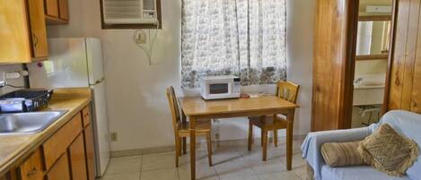 Une cuisine de taille réduite comprenant une table à manger, des chaises, un four à micro-ondes et un évier.