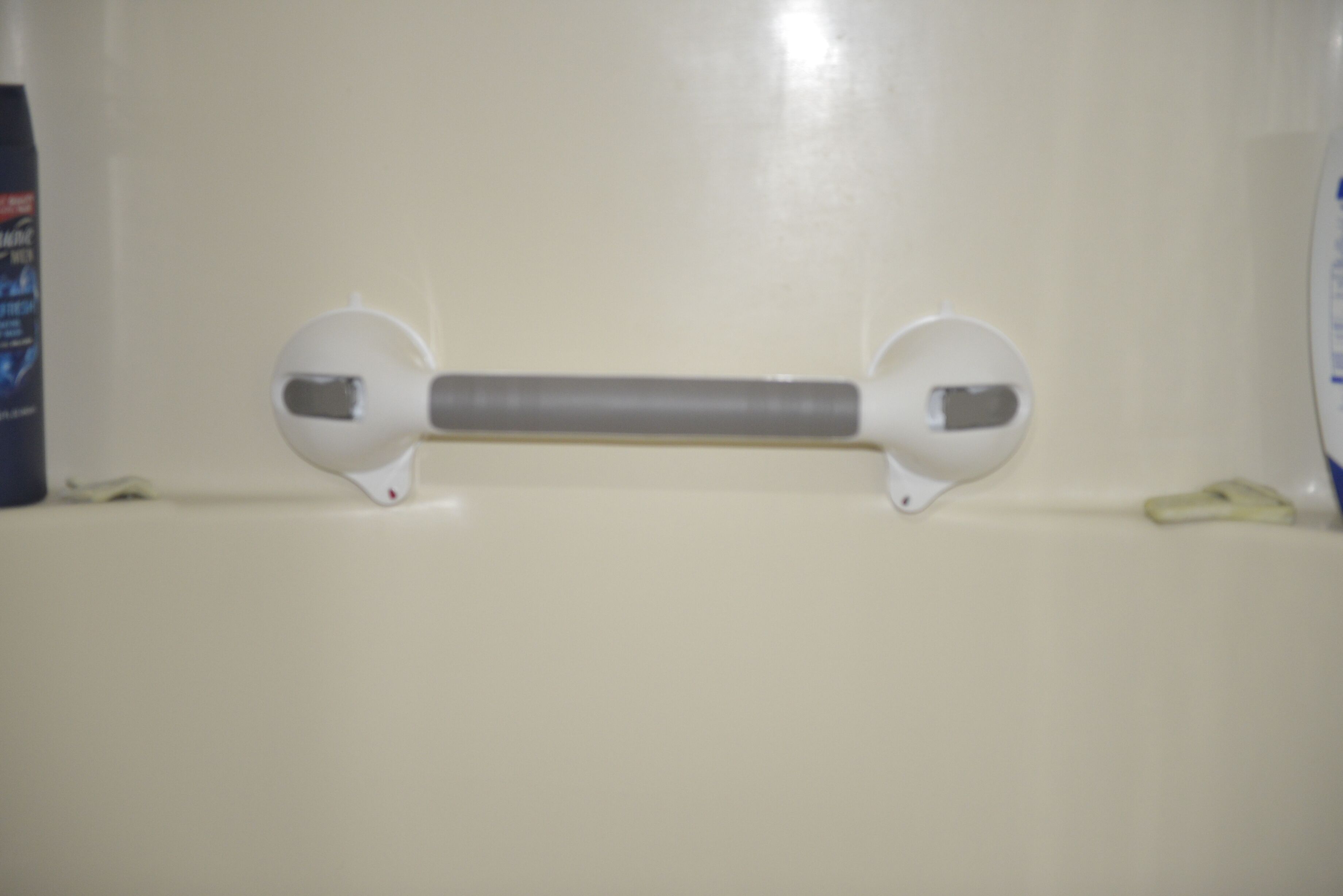 Un baño con inodoro blanco, toallero blanco y dispensador de jabón blanco.
